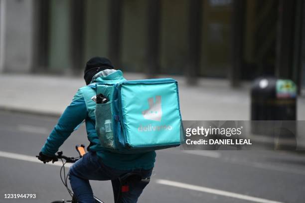 Deliveroo rider cycles through central London on March 26, 2021. - The meal delivery platform Deliveroo is bracing for strikes and other social...