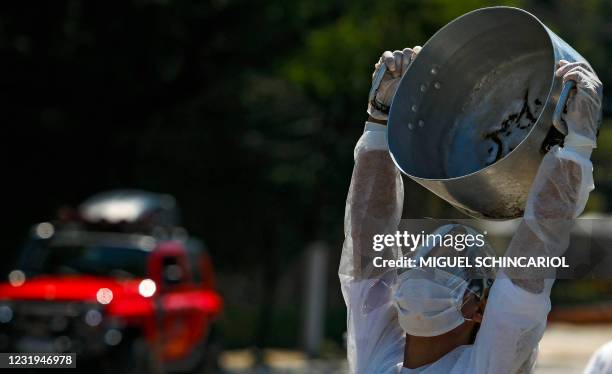 Demonstrator performs as part of the "Empty Pots" movement at the Paraisopolis slum in Sao Paulo, Brazil, on March 26 amid teh COVID-19 pandemic. -...