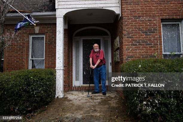 Ken Jannot stands in front of his home on March 26 after a tornado that hit the Eagle Point community damaged the house, south of Birmingham,...
