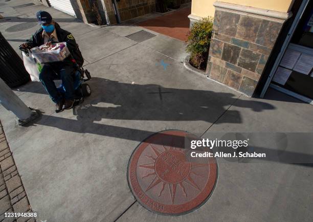 East Los Angeles, CA Mario Flores, of East Los Angeles, sells nuts next to a sundial plaque honoring the accomplishments of Graciela Beltrán, a...