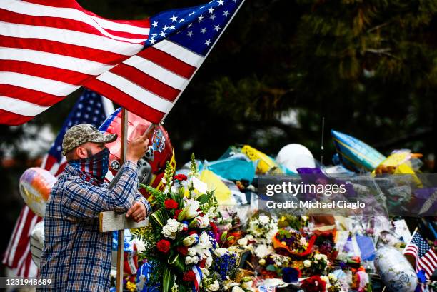 Man who drove in from Indiana carries a cross and an American flag as he pays his respects to slain Boulder Police officer Eric Talley at a makeshift...