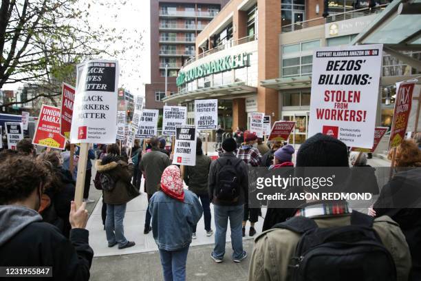 People hold pro-worker signs and rally outside a Whole Foods Market after marching from Amazon headquarters in solidarity with Amazon workers in...