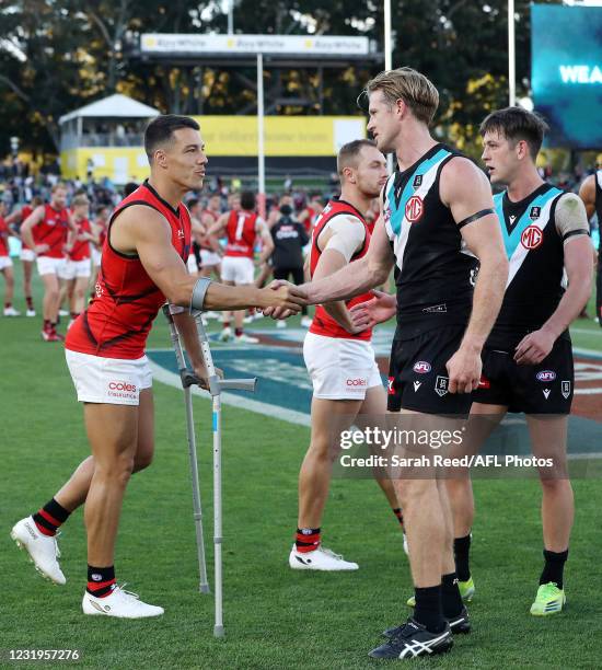 Dylan Shiel of the Bombers shakes hands with Tom Jonas of the Power after the game during the 2021 AFL Round 02 match between the Port Adelaide Power...