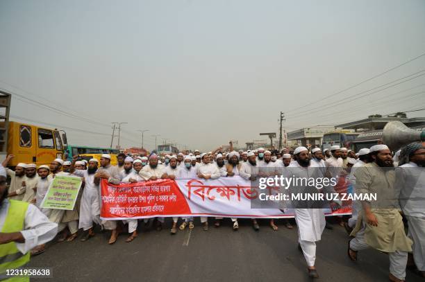 Activists of the Hefazat-e Islam, a hard-line islamist group, walk behind a banner along a road during a demonstration on the outskirts of Dhaka on...