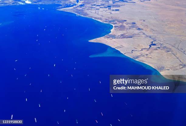 An aerial view taken on March 27, 2021 from the porthole of a commercial plane shows stranded ships waiting in queue in the Gulf of Suez to cross the...
