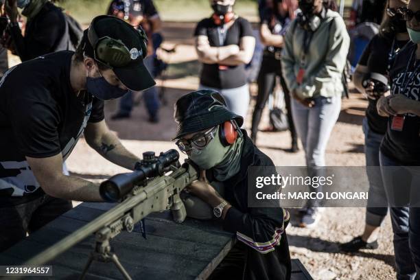 Technician helps a gun enthusiast to adjust her firing position behind a South African made Truvelo .308 CMS precision rifle at the Rooikraal...