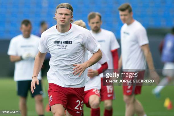 Norway's forward Erling Braut Haaland wears a t-shirt with the slogan 'Human rights, on and off the pitch' as he warms up before the FIFA World Cup...