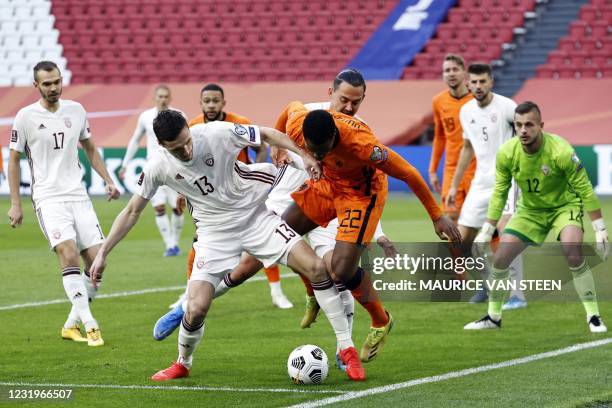 Latvia's Defender Raivis Jurkovskis fights for the ball against Dutch defender Denzel Dumfries during their World Cup qualifying Group G match...