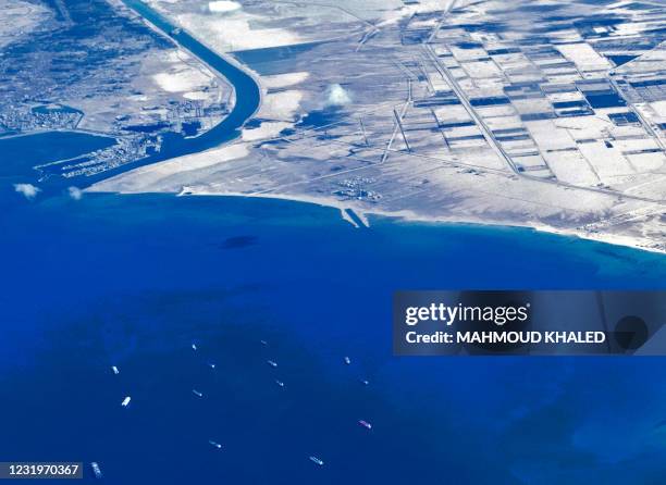 An aerial view taken on March 27, 2021 from the porthole of a commercial plane shows stranded ships waiting in queue in the Gulf of Suez to cross the...