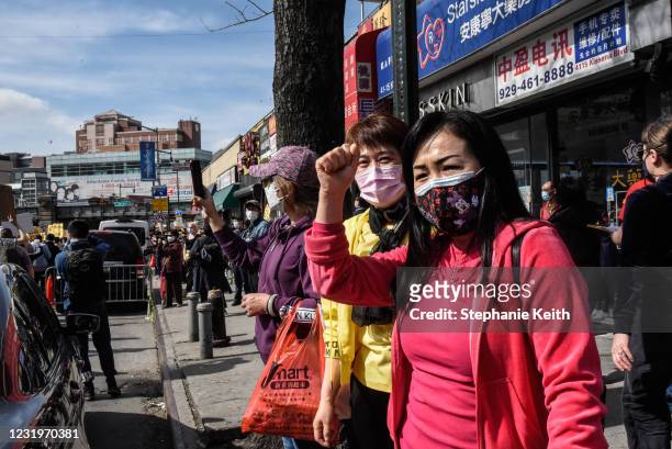 Bystanders watch as demonstrators march against anti-Asian violence through the streets on March 27, 2021 in the Flushing neighborhood in the Queens...