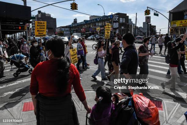 Bystanders watch as demonstrators march against anti-Asian violence through the streets on March 27, 2021 in the Flushing neighborhood in the Queens...