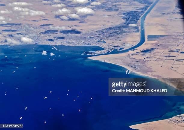 An aerial view taken on March 27, 2021 from the porthole of a commercial plane shows stranded ships waiting in queue in the Gulf of Suez to cross the...