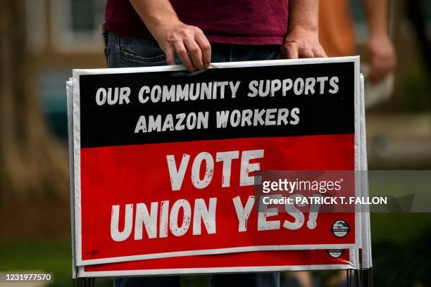 Person holds "Vote Union Yes!" signs during a protest in solidarity with Black Lives Matter, Stop Asian Hate and the unionization of Amazon.com, Inc....