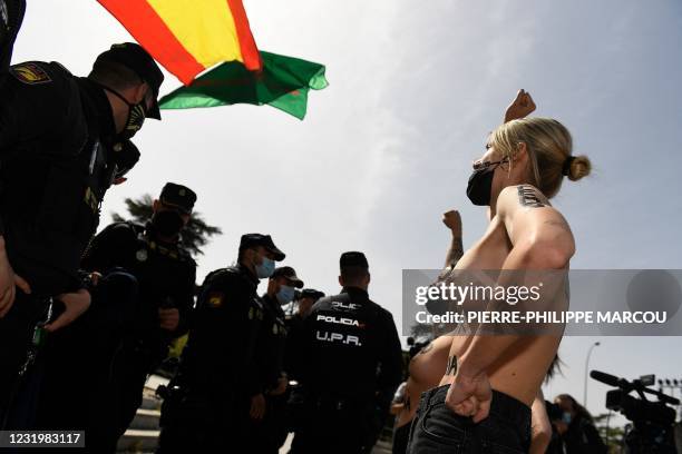 Graphic content / Spanish police officers stand guard opposite Femen activists shouting slogans during a demonstration against a far-right Francoist...