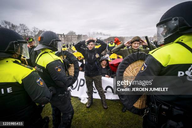 Dutch riot police watch campaigners in military clothing as they gather with protesters on the Museumplein for the so-called Coffee Drink campaign to...