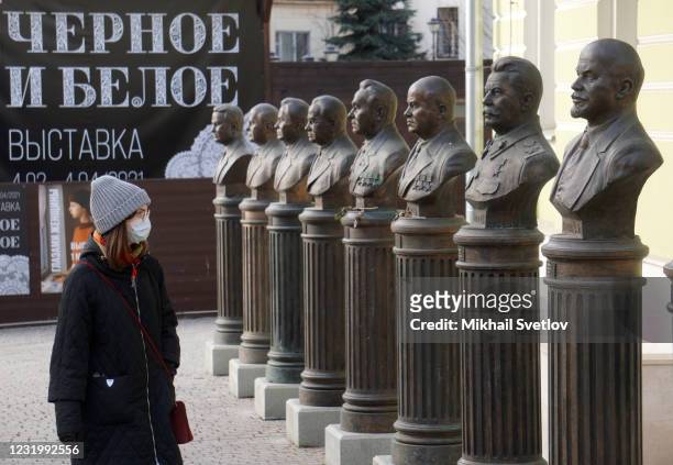 Woman wearing face mask to protect herself against the coronavirus looks at monuments to Vladimir Lenin, Joseph Stalin and other Soviet and Russian...