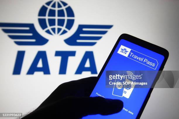 In this photo illustration, Travel Pass app of a mobile application by IATA seen displayed on a smartphone screen in front of IATA logo. Travel Pass...