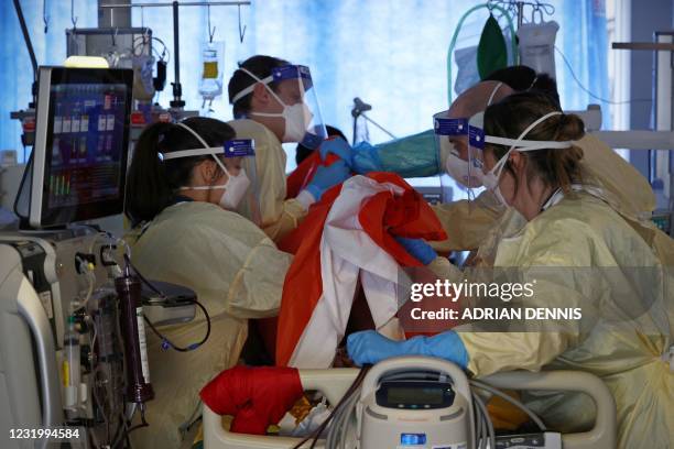 Firefighters Dan Joslin and Tom Ventress work alongside critical care nurses to prone a Covid-19 patient in the Intensive Care Unit at Queen...