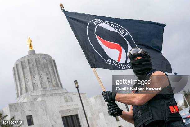 Protester waves an anti-fascist flag at the Oregon statehouse on March 28, 2021 in Salem, Oregon. The protesters clashed with occupants of vehicles...