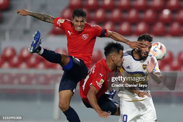 Carlos Tevez of Boca Juniors jumps for a header with Gaston Togni and Lucas Romero of Independiente during a match as part of Copa de la Liga...