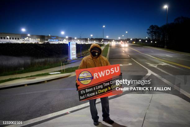 Union supporter stands before sunrise outside the Amazon.com, Inc. BHM1 fulfillment center on March 29, 2021 in Bessemer, Alabama. - Votes are set to...