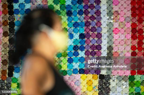 Woman waits to receive a dose of coronavirus vaccination in front of the panel in honor of the fatal victims of the disease amidst the coronavirus...