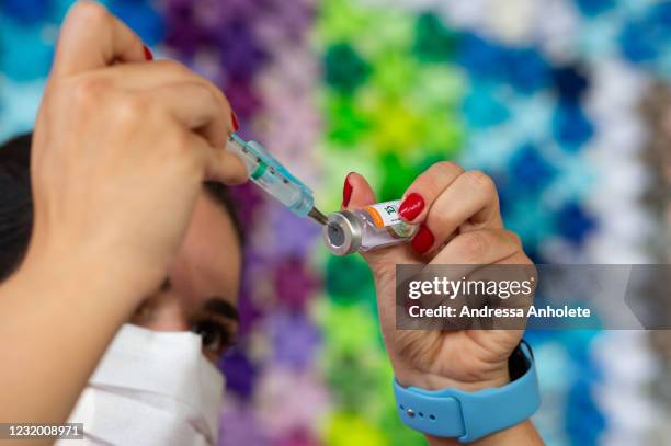 Health professional prepares a vaccine against coronavirus in front of the panel in honor of the fatal victims of the disease amidst the coronavirus...