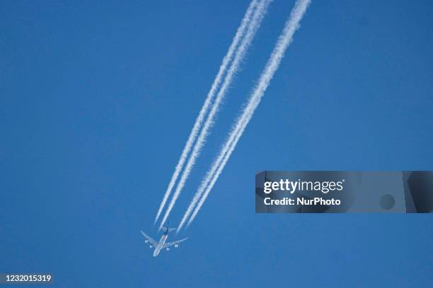 Boeing 747-8F aircraft as seen flying in the blue sky over the Netherlands. The overflying Jumbo Jet airplane is cruising at high altitude leaving...