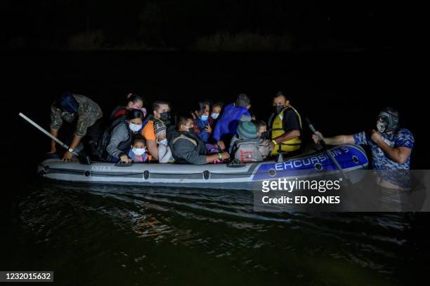 Coyote' people smuggler guides an inflatable boat carrying migrants from Central America arriving illegally from Mexico to the US to seek asylum, on...