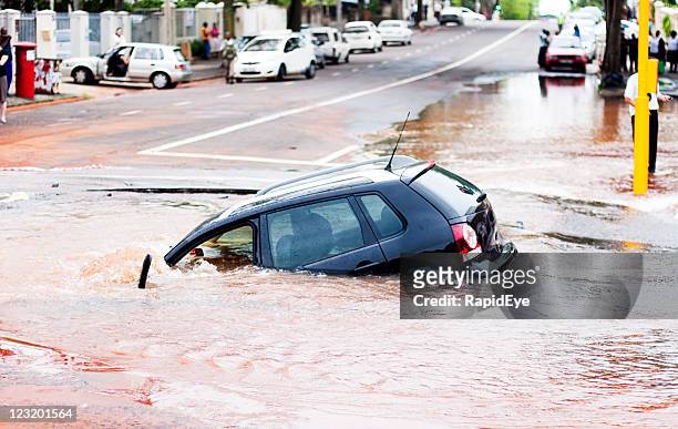 car tips into pothole in flooded street, side view - flood city stock pictures, royalty-free photos & images