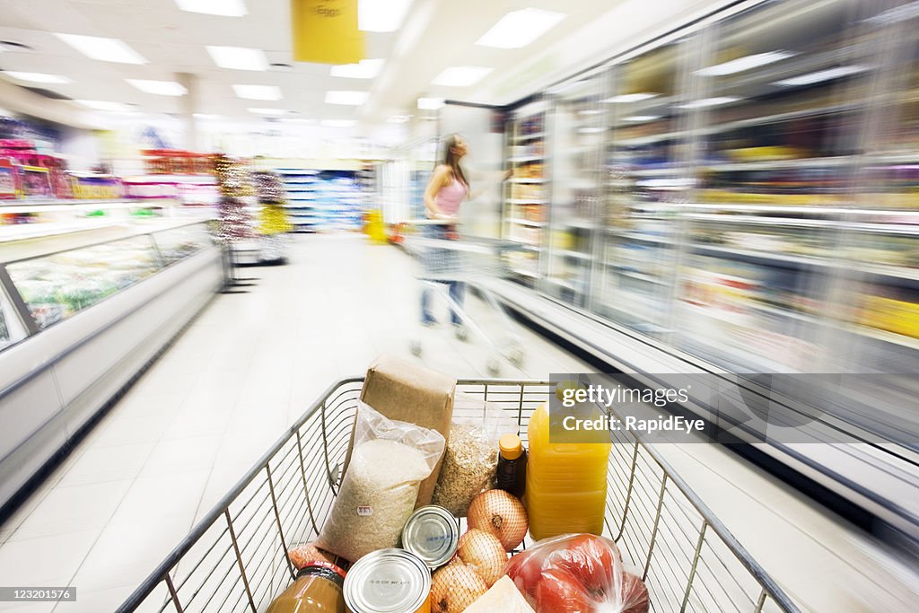 Supermarket trolley moves through fridge area showing motion blur