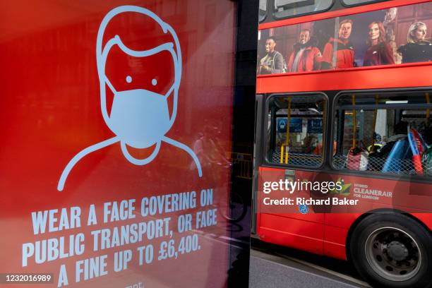 London bus carrying ads for a TV channel drives past a government ad, warning of fines if passengers do not wear face coverings during the third...