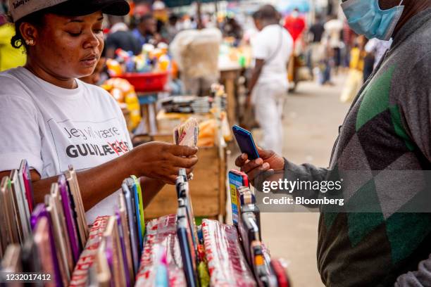 Vendor counts out Nigerian naira banknotes for the purchase of a second-hand mobile phone from a kiosk at the Ikeja computer village market in Lagos,...