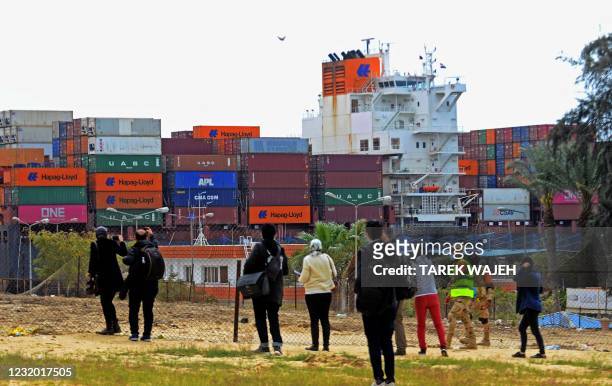 Journalists look at a container ship navigating Egypt's Suez Canal on March 30 a day after the Ever Given cargo vessel was dislodged from its banks....