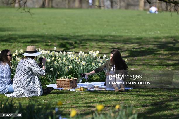 People enjoy a picnic alongside daffodils in Greenwich Park, southeast London on March 30 as England's third Covid-19 lockdown restrictions ease,...