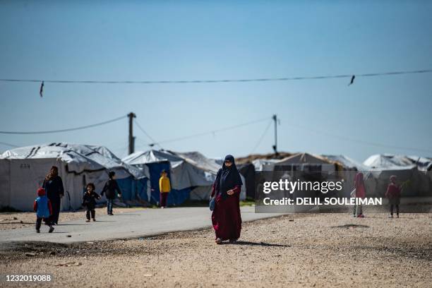 Women with children walk at Camp Roj, where relatives of people suspected of belonging to the Islamic State group are held, in the countryside near...