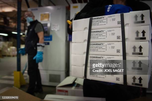 Employees unpack boxes of the Pfizer/BioNTech vaccine in front of freezers at an AGEPS of the Paris public hospitals warehouse in the Paris suburbs...