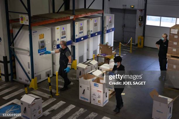 Employees unpack boxes of the Pfizer/BioNTech vaccine in front of freezers at an AGEPS of the Paris public hospitals warehouse in the Paris suburbs...