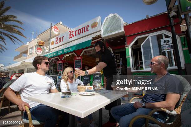 Tourists have drinks at the terrace of a restaurant in Palma Beach in Palma de Mallorca on March 29, 2021. - Bookings for the Balearics surged after...