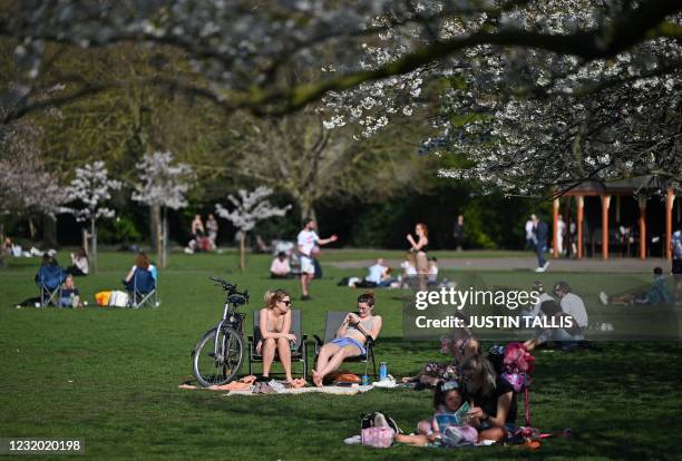 People enjoy the sunshine in Battersea Park, central London on March 30 as England's third Covid-19 lockdown restrictions eased on March 29, allowing...