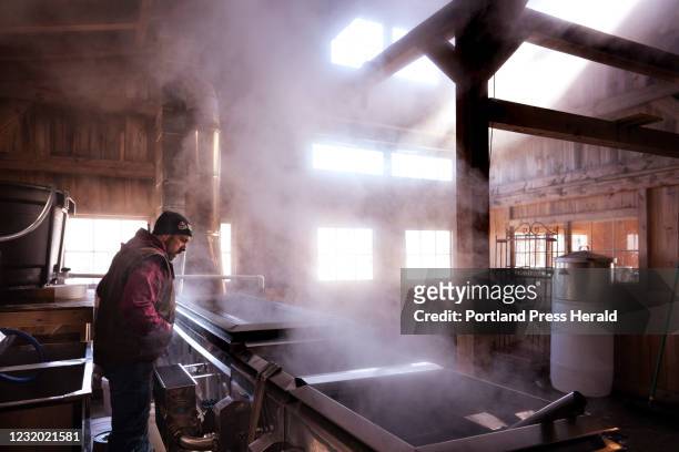 Keith Harris checks on maple sap boiling in an evaporator in a sugarhouse at Harris Farm in Dayton on Friday, March 19, 2021.