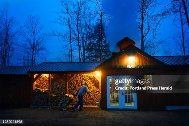 Terry Deering of Gorham brings wood into the sugarhouse as steam rises from the vents as he and Scott Dunn boil sap at Dunn Family Maple in Buxton...