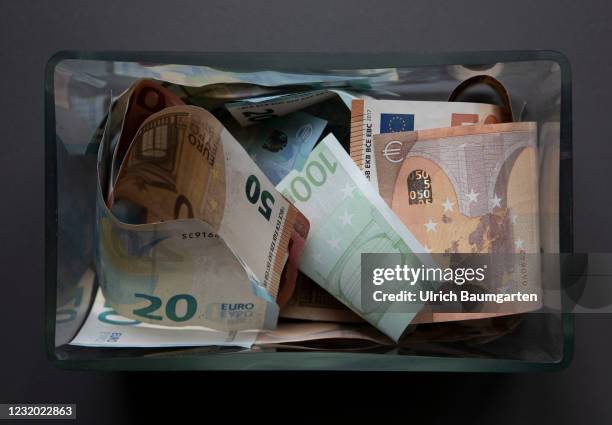 This photo illustration shows a rectangular glass vase filled with various euro banknotes on March 30, 2021 in Bonn, Germany.