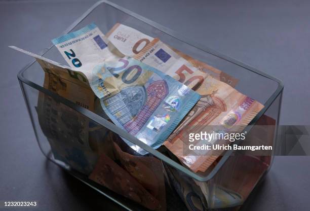 This photo illustration shows a rectangular glass vase filled with various euro banknotes on March 30, 2021 in Bonn, Germany.