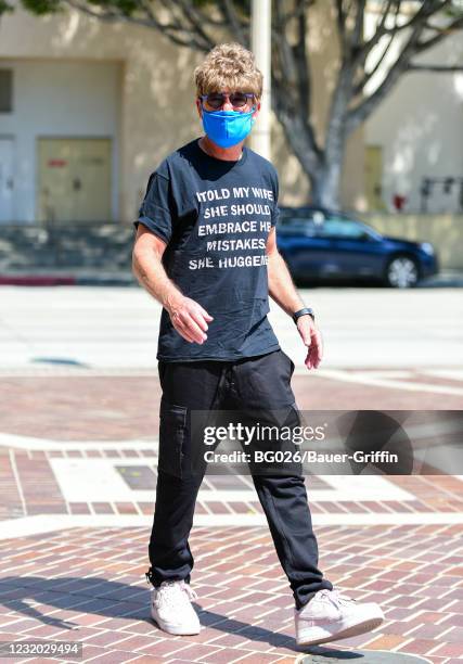 Howie Mandel is seen wearing a wig, sunglasses and a t-shirt with a joke printed on it reading "I told my wife should embrace her mistakes. She...
