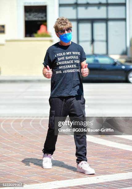 Howie Mandel is seen wearing a wig, sunglasses and a t-shirt with a joke printed on it reading "I told my wife should embrace her mistakes. She...