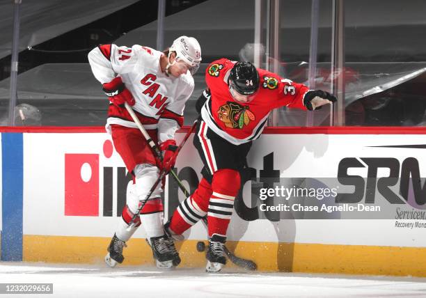 Jake Bean of the Carolina Hurricanes and Carl Soderberg of the Chicago Blackhawks battle for the puck in the first period at the United Center on...