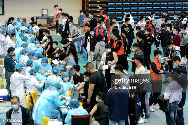 This photo taken on March 30, 2021 shows university students queueing to receive the Sinovac Covid-19 coronavirus vaccine at a university in Qingdao...