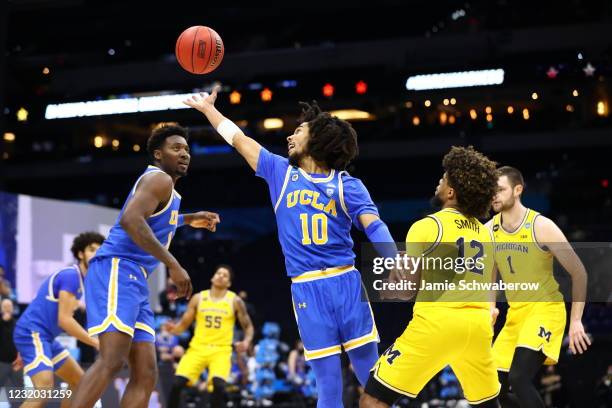 Tyger Campbell of the UCLA Bruins reaches for a ball knocked loose by Mike Smith of the Michigan Wolverines in the Elite Eight round of the 2021 NCAA...