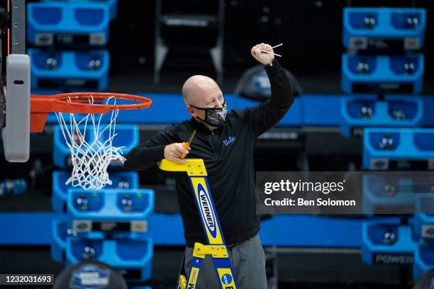 Head coach Mick Cronin of the UCLA Bruins cuts a piece of the net after beating the Michigan Wolverines in the Elite Eight round of the 2021 NCAA...